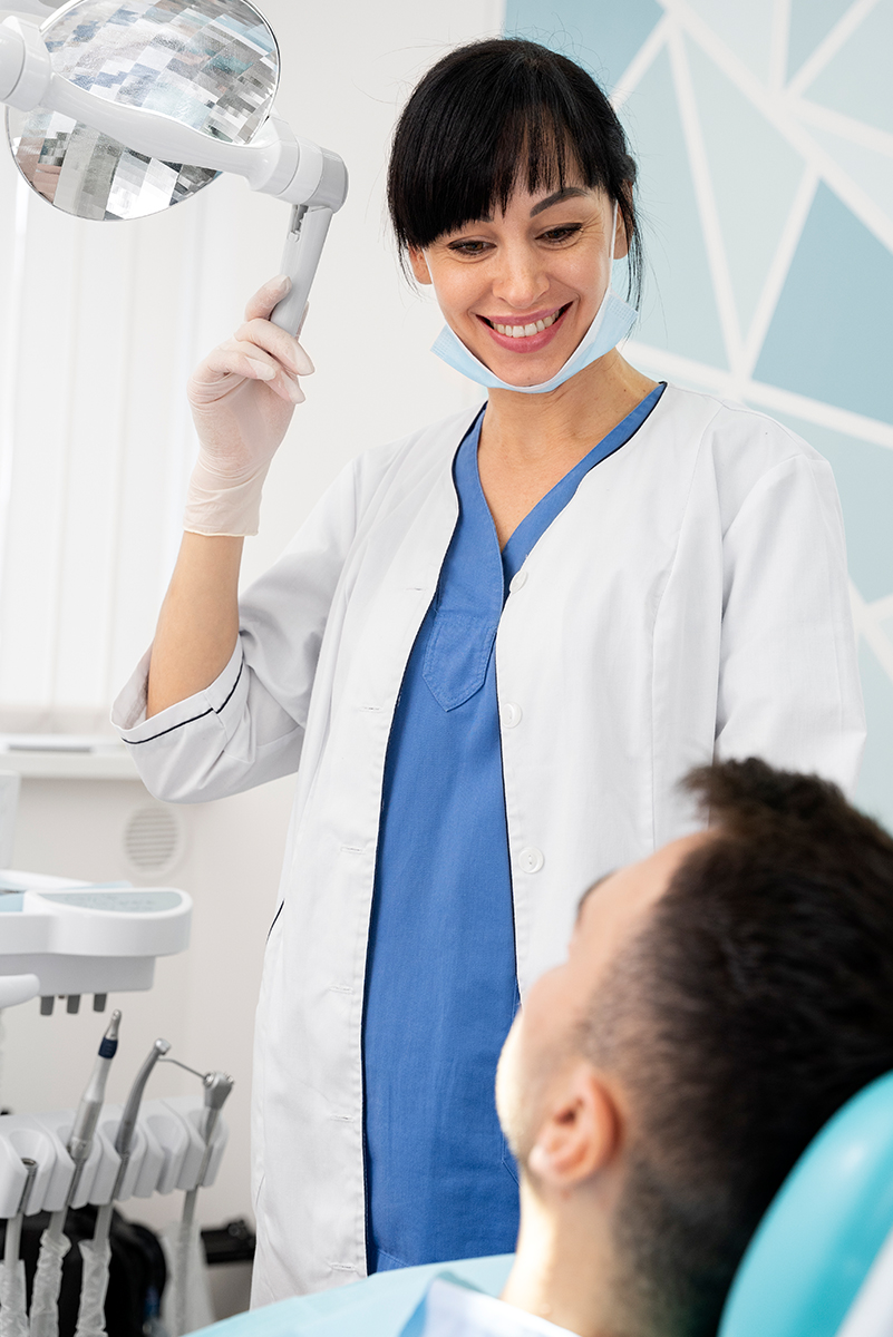 Portrait of a positive young male dentist in uniform with crossed hands at the dental office